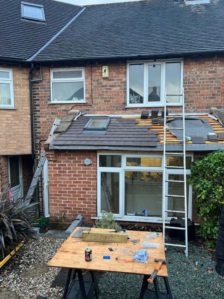 This is a photo of a roof extension that is having new roof tiles installed. This is a photo taken from the roof ridge looking down a tiled pitched roof on to a flat roof. Works carried out by Redhill Roofing Repairs