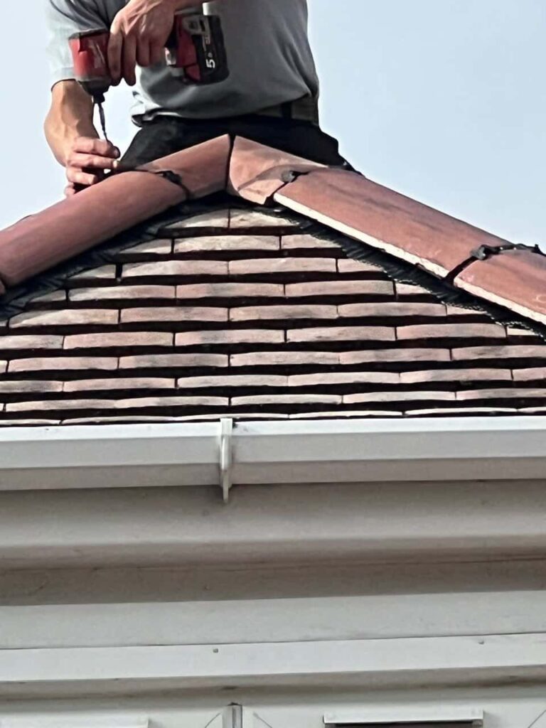 This is a photo of one of the operatives of Redhill Roofing Repairs installing new ridge tiles