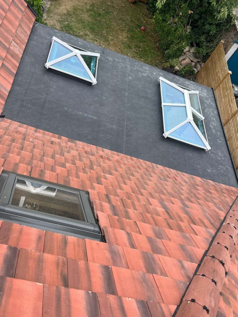 This is a photo taken from the roof ridge looking down a tiled pitched roof on to a flat roof. Works carried out by Redhill Roofing Repairs